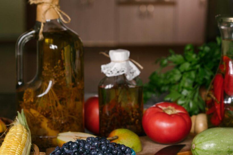 Butelis ypač tyro alyvuogių aliejaus ant medinio stalo virtuvės aplinkoje.