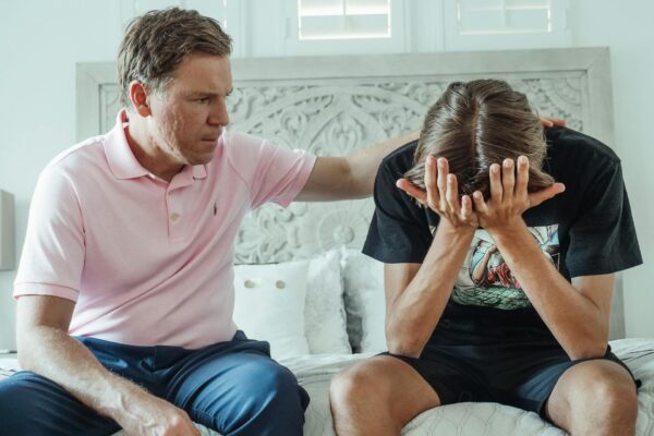 Suaugęs asmuo jautriai guodžia vaiką ramiame namų fone.