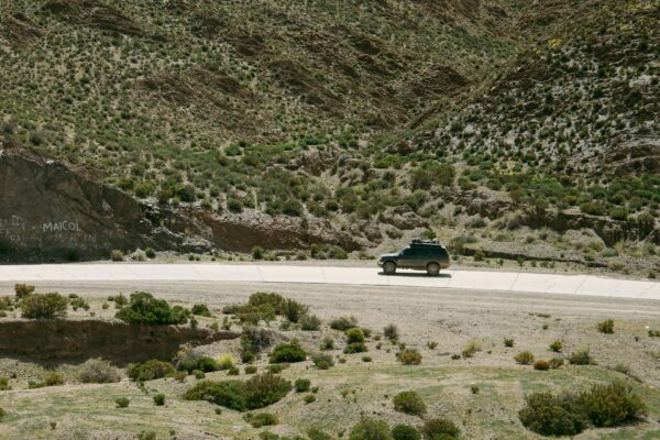 Sidabrinis automobilis važiuojantis vaizdingu Europos kalnų keliu saulėtekio metu.