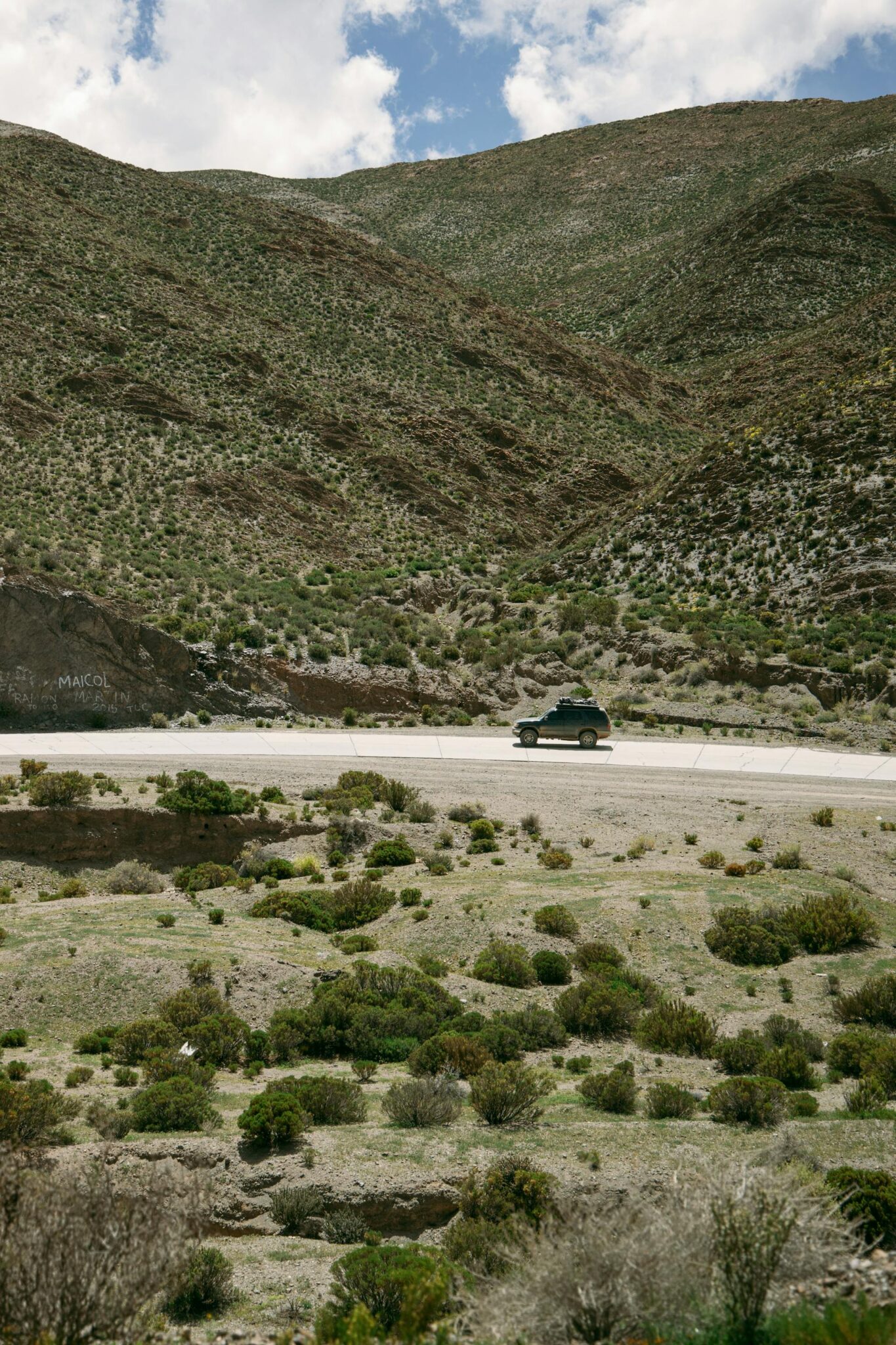 Sidabrinis automobilis važiuojantis vaizdingu Europos kalnų keliu saulėtekio metu.