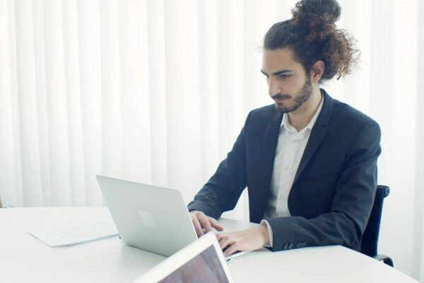 Jaunas verslininkas sėdi prie stalo moderniame biure ir planuoja naujos įmonės steigimo žingsnius.